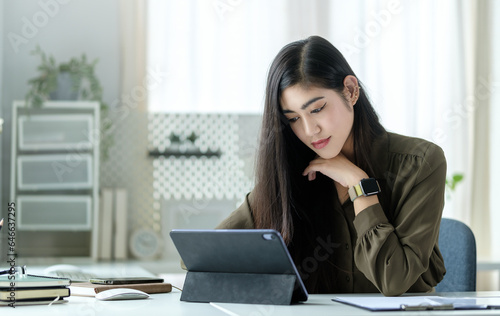 Focused millennial businesswoman reading financial data on digital tablet.