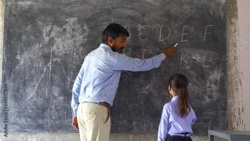 Indian Rural elementary school teacher teaching kids some lesson in the class with excitement and joy.