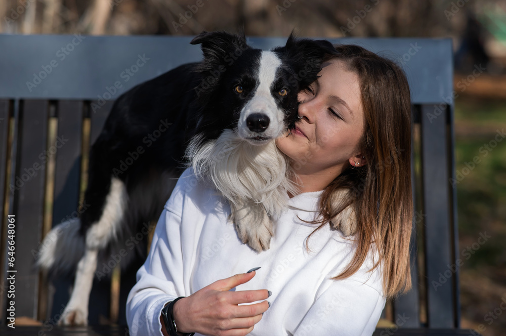 Caucasian woman hugging her dog Border Collie while sitting on a bench in autumn park. Caucasian woman hugging her dog Border Collie while sitting on a bench in autumn park.
