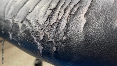 Torn old black leather office chair close up view. Furniture broken and damage concept. Chair spin from left side