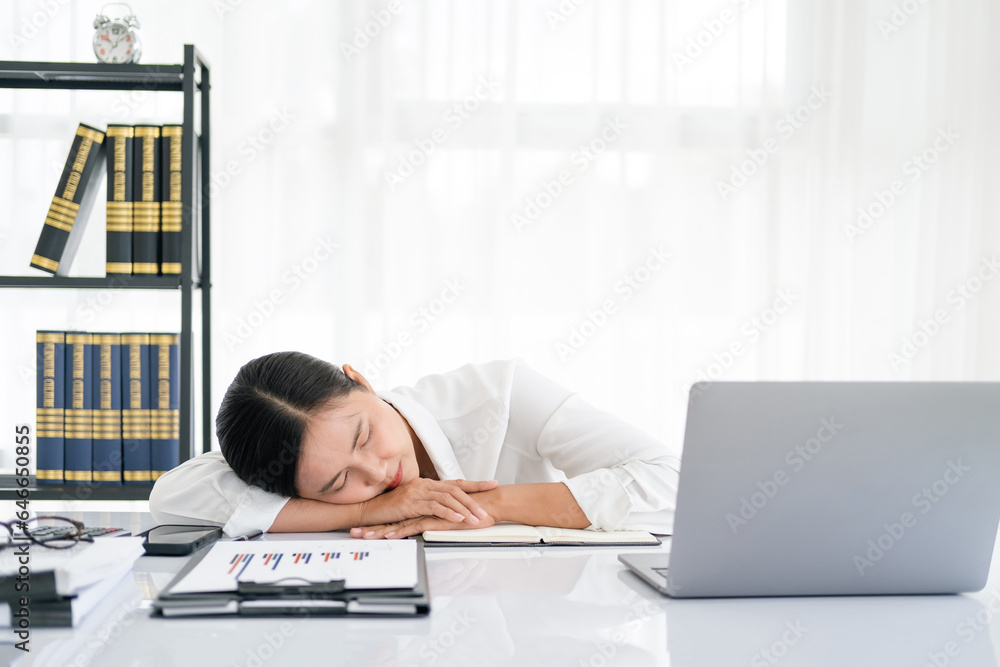 Overworked and tired businesswoman sleeping over a laptop in a desk at work in her office Overworked and tired businesswoman sleeping over a laptop in a desk at work in her office