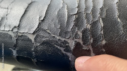 Torn old black leather office chair close up view. Furniture broken and damage concept. Finger inspecting