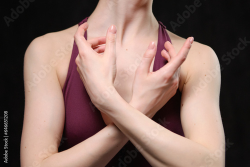 Beautiful faceless ballerina posing in the studio on a black background. Hands perform ballet movements. The photo shows the beauty of classical ballet