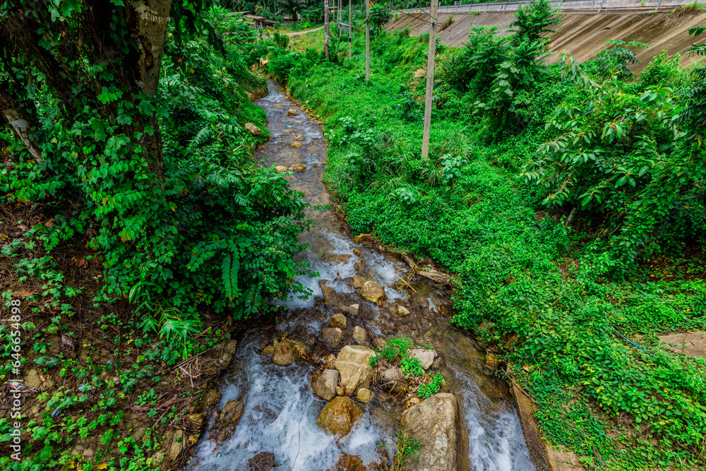 Obraz premium Background of a natural waterfall with cool water flowing from high mountains, Punyaban Waterfall Lamnam Kraburi National Park in Ranong Province, Thailand