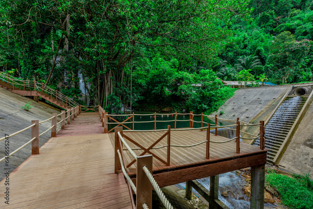 Fototapeta premium Background of a natural waterfall with cool water flowing from high mountains, Punyaban Waterfall Lamnam Kraburi National Park in Ranong Province, Thailand