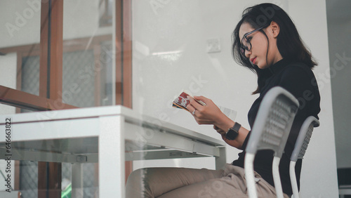 Beautiful asian girl reading a book shot over glass wall with surrounding reflections in a cafe 