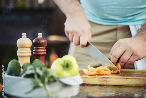 Unrecognizable man slicing sweet bell pepper for salad