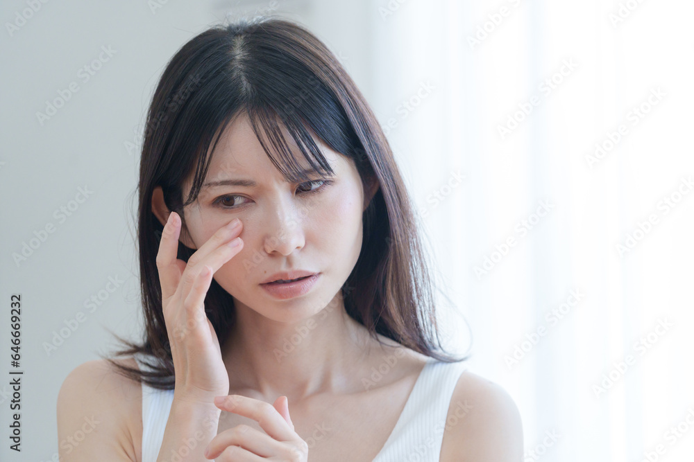 顔の目元に悩む女性 顔の目元に悩む女性