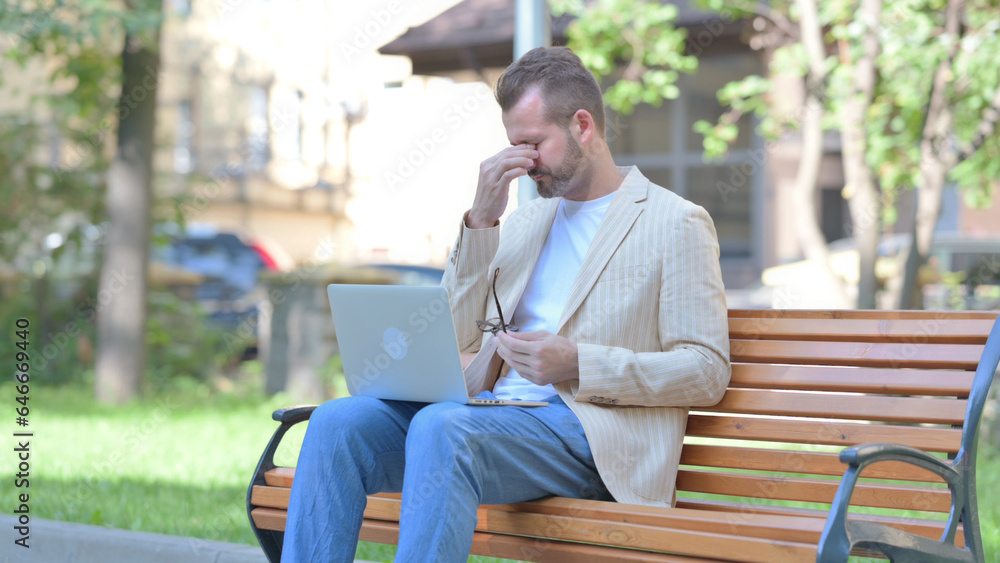 Fototapeta premium Middle Aged Man with Headache Working on Laptop Outdoor