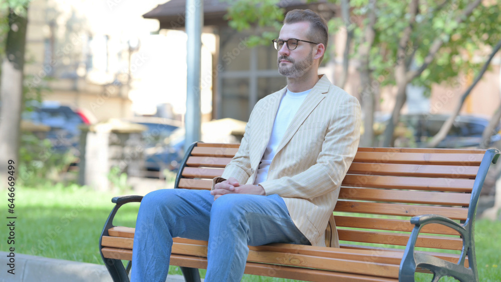Fototapeta premium Serious Middle Aged Man Sitting Outdoor