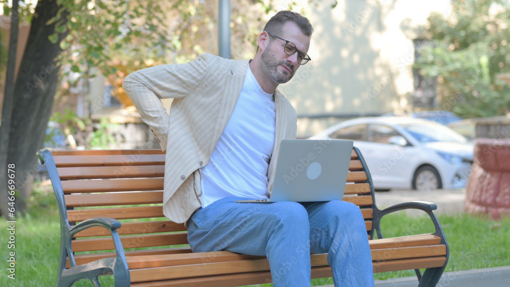 Modern Casual Man Using Laptop with Back Pain while Sitting Outdoor Modern Casual Man Using Laptop with Back Pain while Sitting Outdoor
