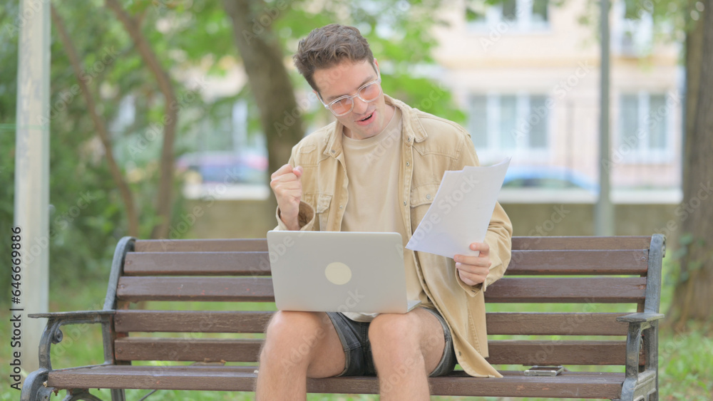Casual Young Man Celebrating while Working on Laptop and Documents Outdoor Casual Young Man Celebrating while Working on Laptop and Documents Outdoor