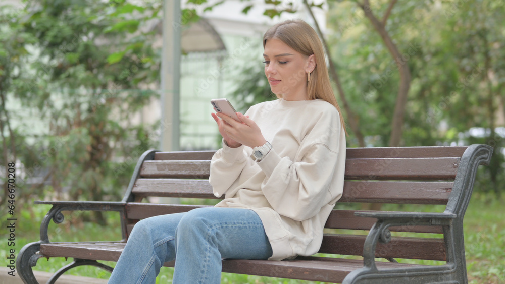 Obraz premium Casual Young Woman using Phone while Sitting Outdoor
