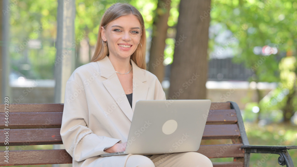 Young Businesswoman Smiling at Camera while Working on Laptop Outdoor