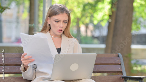 Young Businesswoman Feeling Upset while Reading Contract and Using Laptop Outdoor