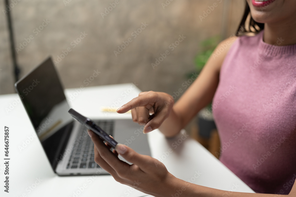 Naklejka premium Asian businesswoman sitting and working with laptop computer Use the phone to talk via video call. online in financial business Business ideas to start online through the media.