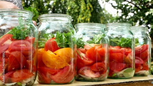 Preservations, conservation. Salted, pickled tomatoes in a jars on an wooden table. Pickling tomatoes at home. Vegetable harvest conservation. Close up.