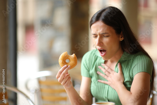 Woman choking eating doughnut in a bar