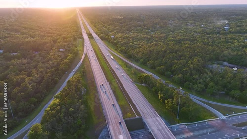 View from above of busy american highway crossroads with fast moving traffic in green Florida area in the evening. Interstate transportation concept