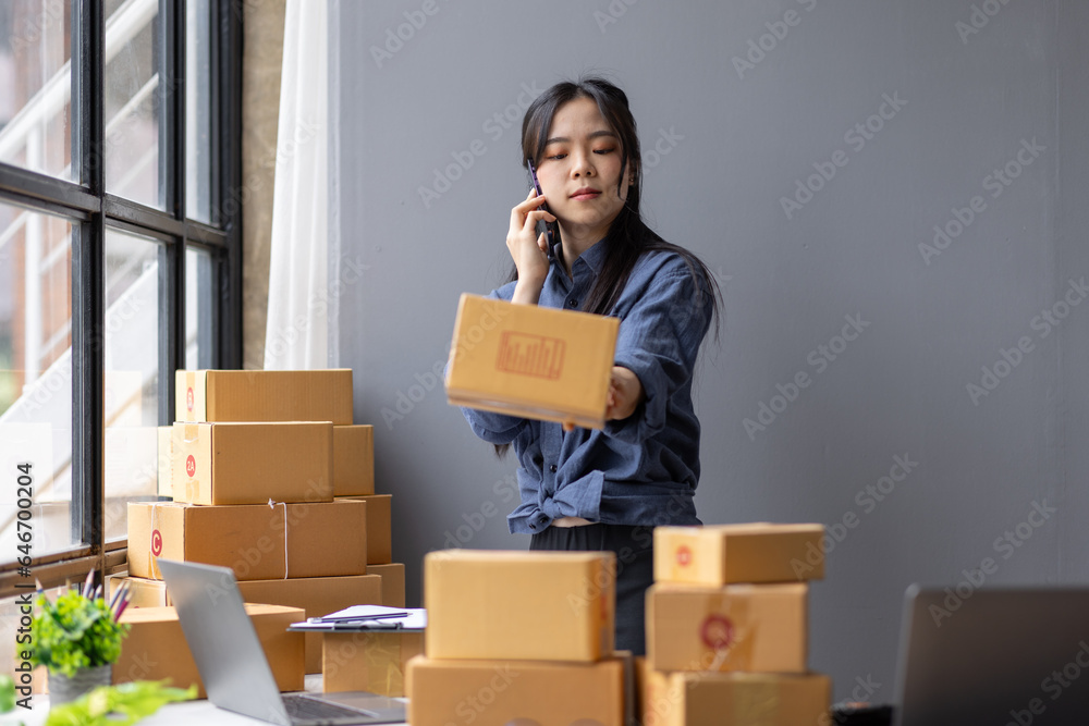 Young Asian woman SME small business owner online shopping at home. taking note of orders from customers with laptop and phone. SME entrepreneur or freelance life style concept. Young Asian woman SME small business owner online shopping at home. taking note of orders from customers with laptop and phone. SME entrepreneur or freelance life style concept.