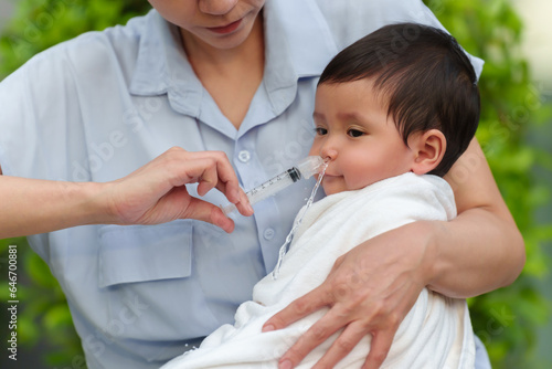 Photography mother making nasal wash for infant with syringe and saline