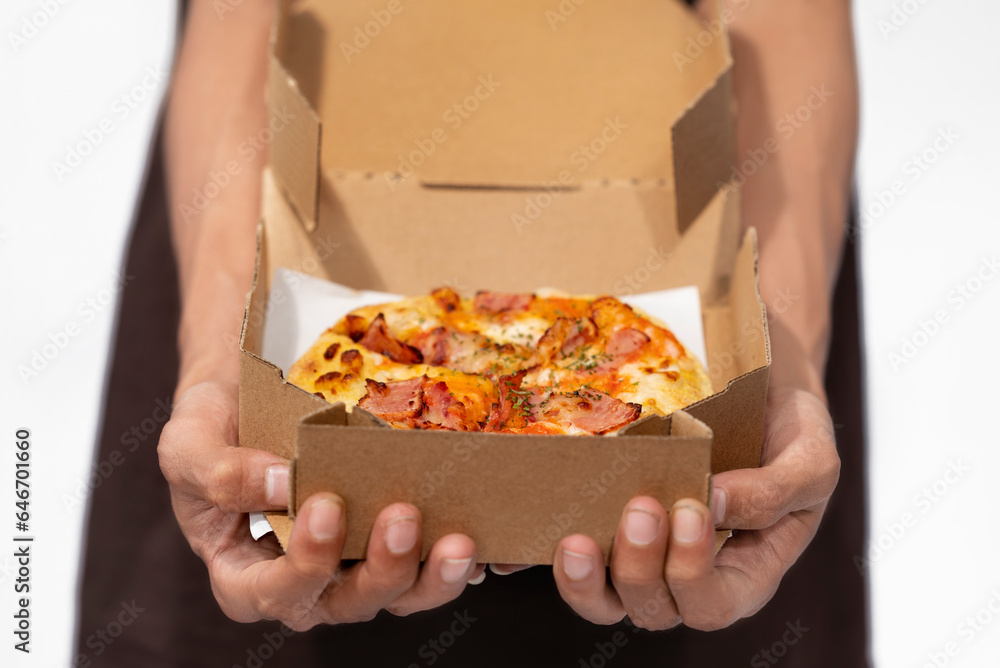 A human hand holding pizza on a cardboard box