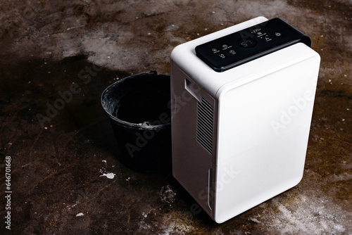 The dehumidifier with a touch panel works in the basement after filling with water. Air dryer. photo