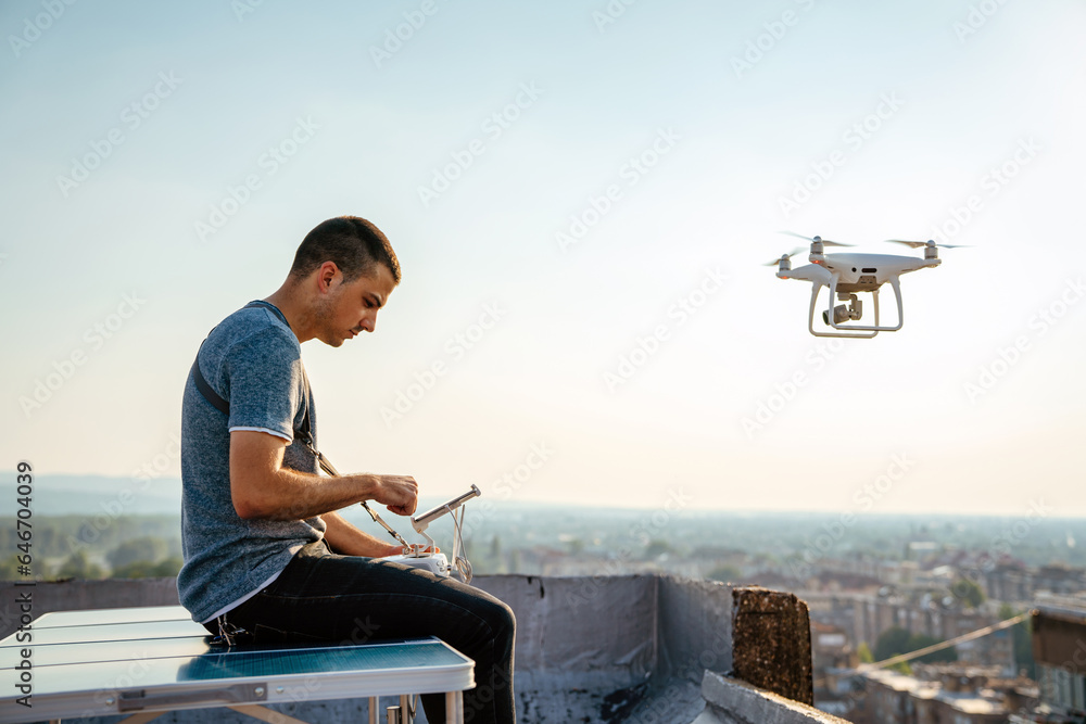 Young technician man flying UAV drone with remote control in city