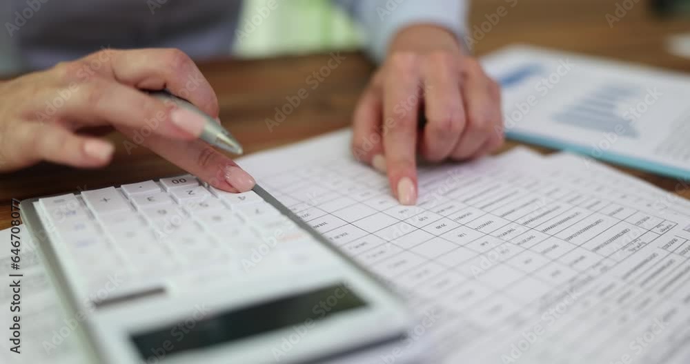 Female hand of marketer or accountant holds pen and presses numbers on acalculator and checks report. Financial statistics and report Female hand of marketer or accountant holds pen and presses numbers on acalculator and checks report. Financial statistics and report