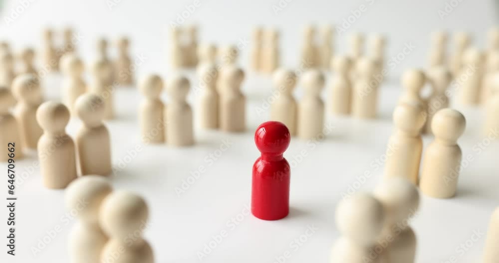 Red figure stands out from crowd with white figures on surface of wooden table. Leadership in modern society and special person Red figure stands out from crowd with white figures on surface of wooden table. Leadership in modern society and special person