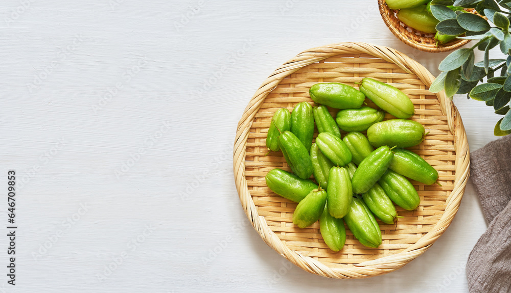 flat lay overhead top view green bilimbi kamias fruit in bamboo plate on white wood table background. green bilimbi kamias on white background. green bilimbi kamias white food table light mood flat lay overhead top view green bilimbi kamias fruit in bamboo plate on white wood table background. green bilimbi kamias on white background. green bilimbi kamias white food table light mood