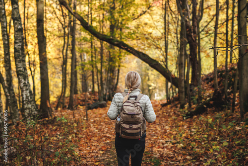 Woman with backpack hiking on footpath in autumn forest. Solo female tourist outdoors © encierro