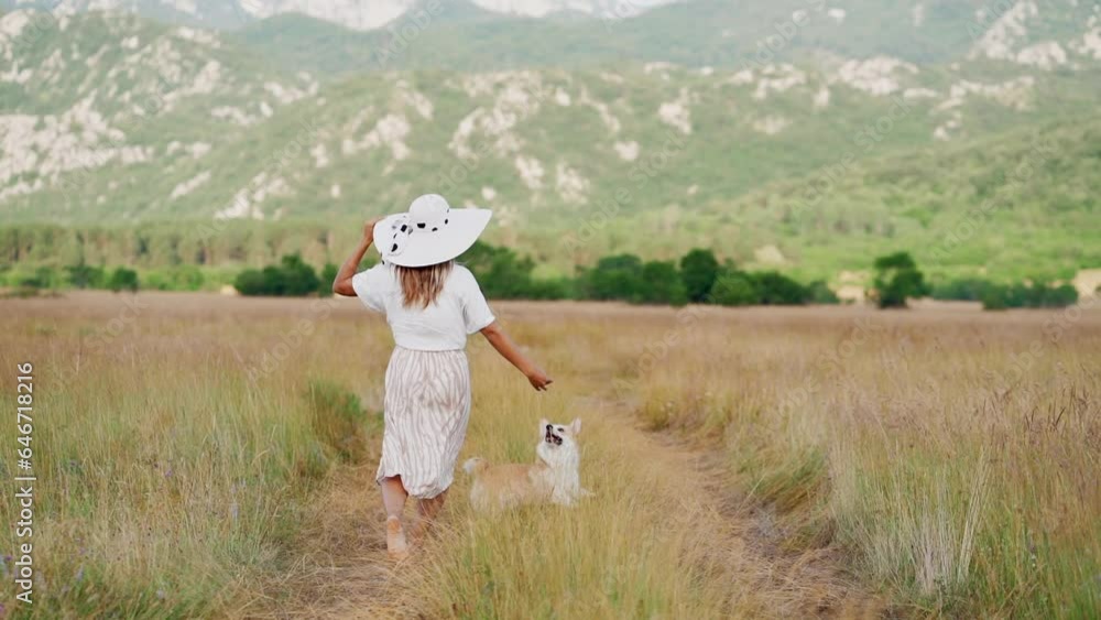 Happy girl running with dog. Pembroke Corgi with woman in nature on the field in summer