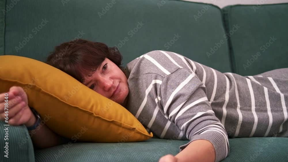 A woman lies on the sofa lazily switching channels. Emotional burnout in a woman. A woman lies on the sofa lazily switching channels. Emotional burnout in a woman.