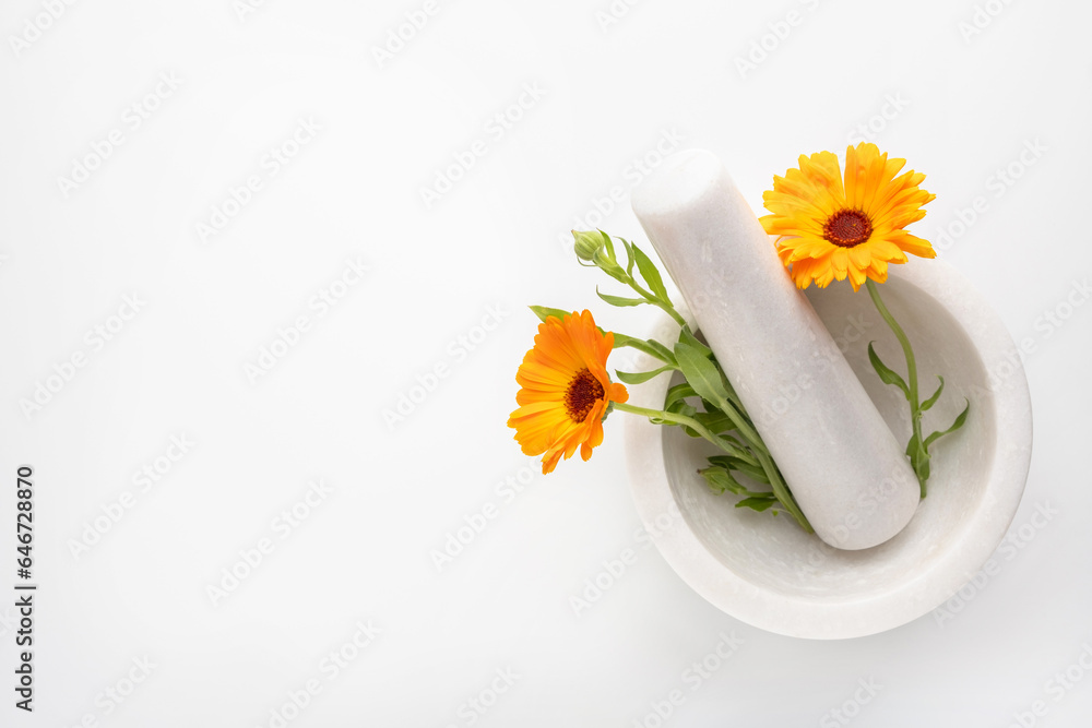 Calendula officinalis flowers in mortar on white background. Marigold medicinal plant, herbal medicine, naturopathy and phytotherapy. Ingredient for natural beauty products and cosmetics. - obrazy, fototapety, plakaty 