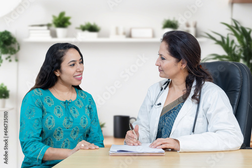 Young indian woman consults about her problem with female gynecologist doctor in modern clinic.