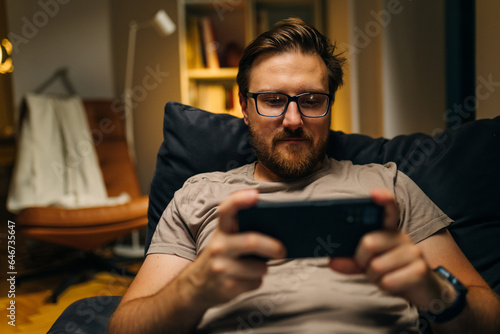 Front view of an adult man playing video game on his phone.