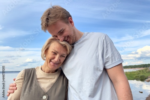 Happy couple or mother with her son walking outdoors on natural sea or lake background 