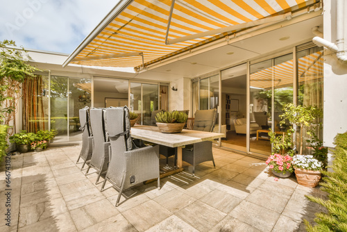 a patio with an umbrella over the dining table and chairs, in front of a large sliding glass door that opens out to a