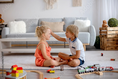 Two sweet children, siblings, playing with trains at home