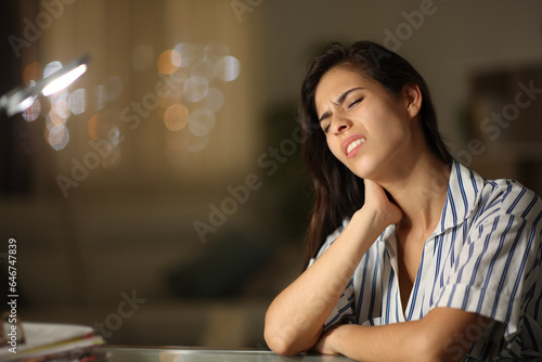Fototapeta Stressed woman suffering neck ache in the night at home