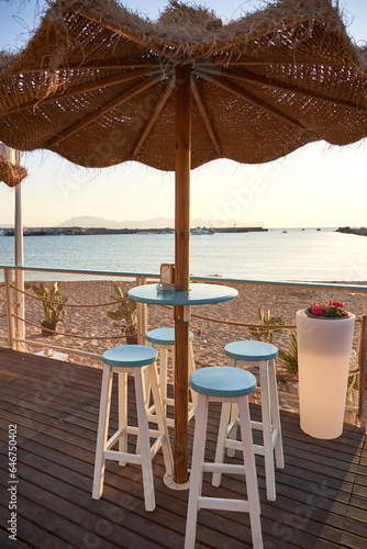 View on empty bar table against sunset at the beach. Summer time in Italy