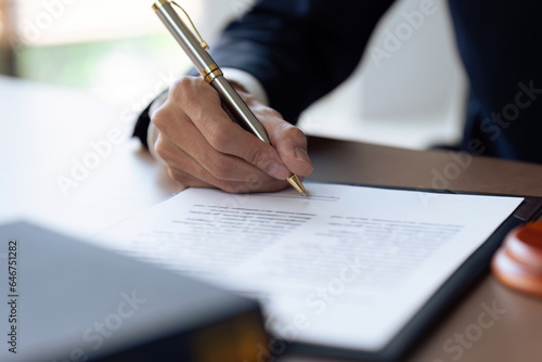 businessman with a suit signing a document with his pen by writing down his signature