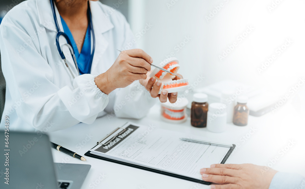 Concentrated dentist sitting at table with jaw samples tooth model and working with tablet and laptop in dental office professional dental clinic. medical doctor working . Concentrated dentist sitting at table with jaw samples tooth model and working with tablet and laptop in dental office professional dental clinic. medical doctor working .