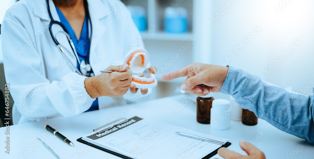 Concentrated dentist sitting at table with jaw samples tooth model and working with tablet and laptop in dental office professional dental clinic. medical doctor working . Concentrated dentist sitting at table with jaw samples tooth model and working with tablet and laptop in dental office professional dental clinic. medical doctor working .