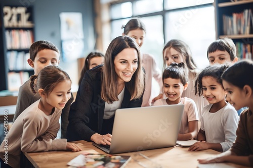 female teacher and student kids watching video together with laptop talking and laughing at class