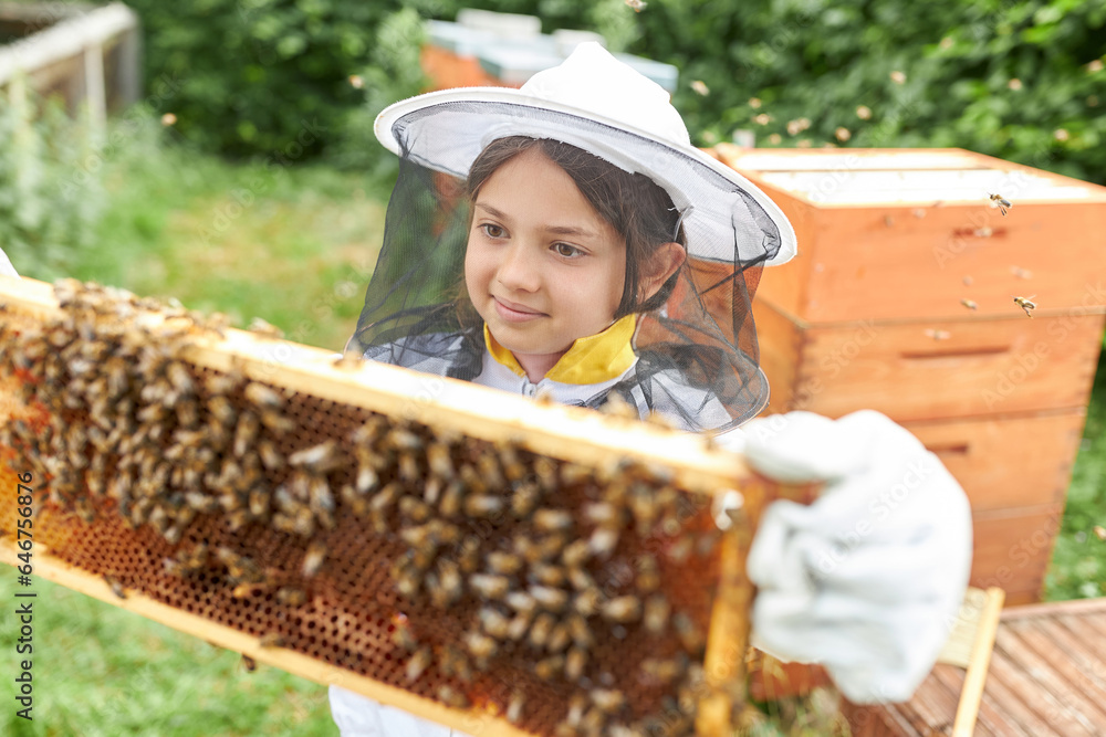 Obraz premium Girl analyzing beehive frame with honey bees amidst smoke