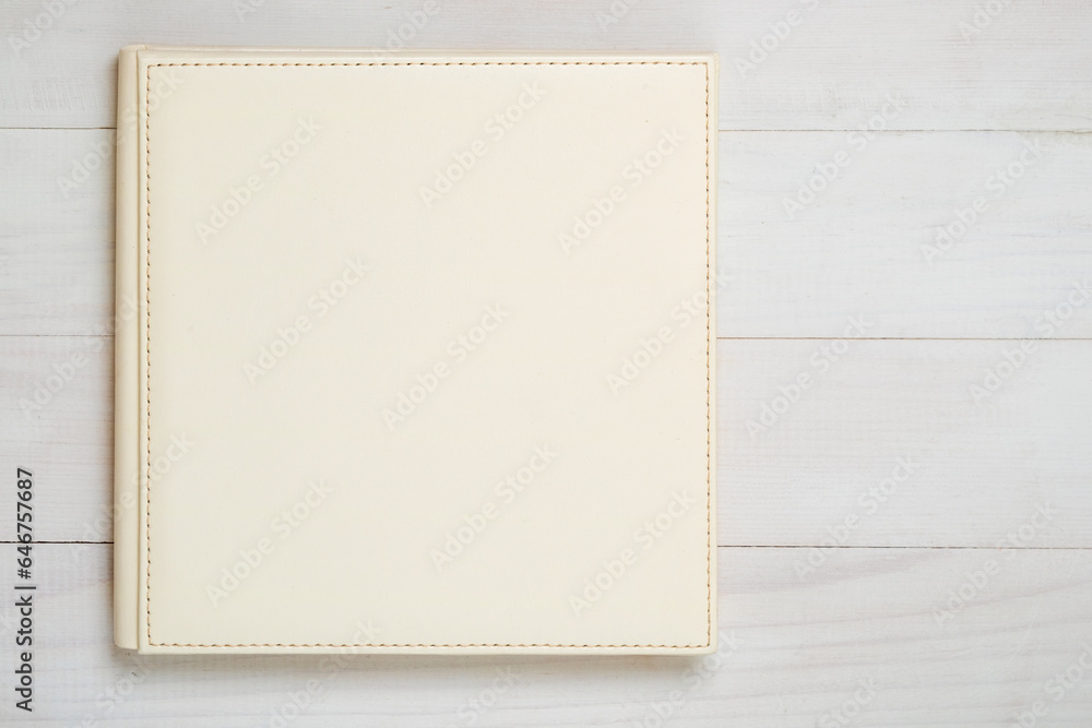 Family photo album on the wood table. Photo book from white color eco leather, top view. Family photo album on the wood table. Photo book from white color eco leather, top view.