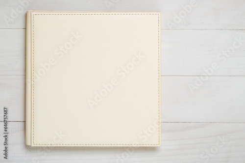 Family photo album on the wood table. Photo book from white color eco leather, top view.