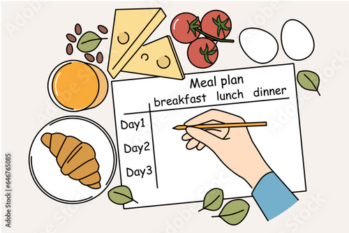 Meal plan on table of nutritionist near ingredients for preparing beneficial food and person hand with pencil. Human prepares meal plan for weight loss or low-calorie diet with healthy effect